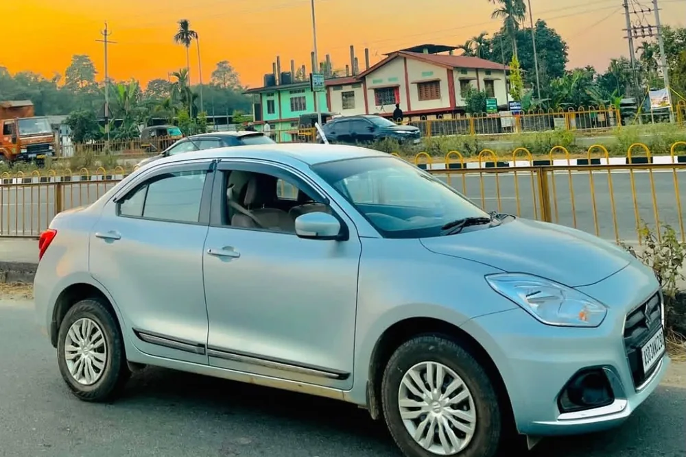 Real MD Cabs Maruti Suzuki Dzire sedan on an Assam highway at sunset